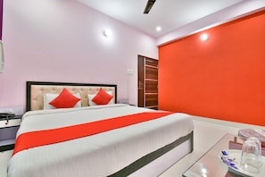A hotel room with a bed, a nightstand, a bedside table, a mirror, and a wardrobe. - Hotel O by OYO Magadh Imperial (Patna)