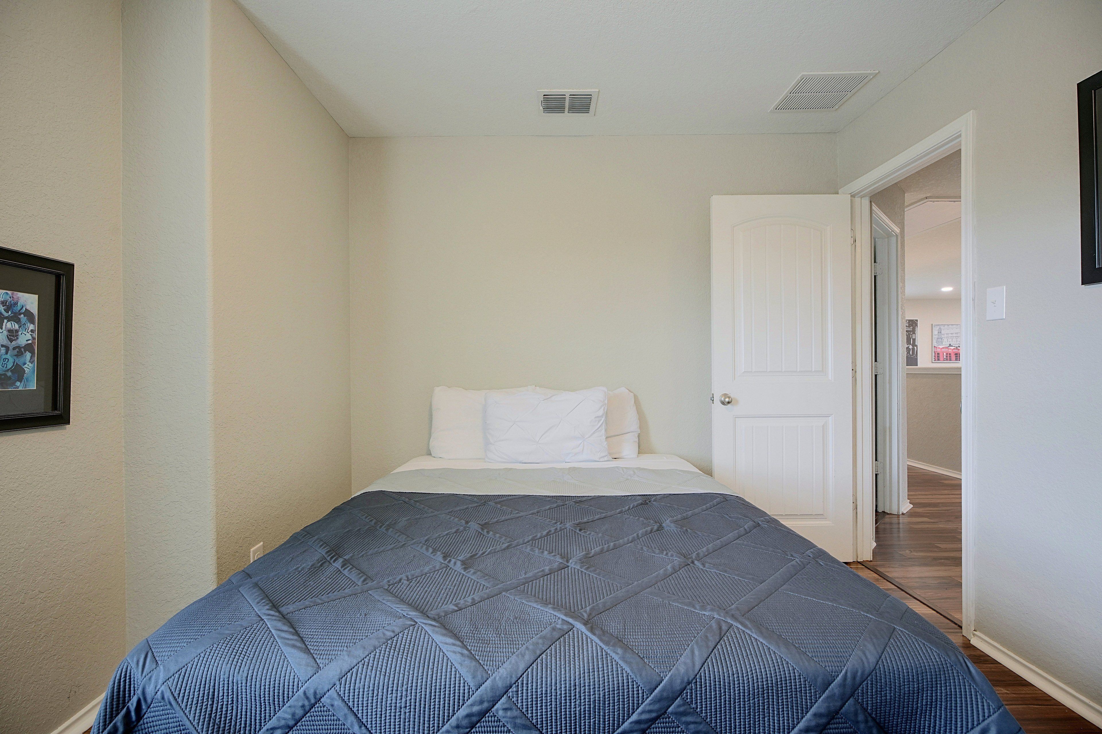 Un dormitorio con cama, puerta y pasillo que conduce a otra habitación.