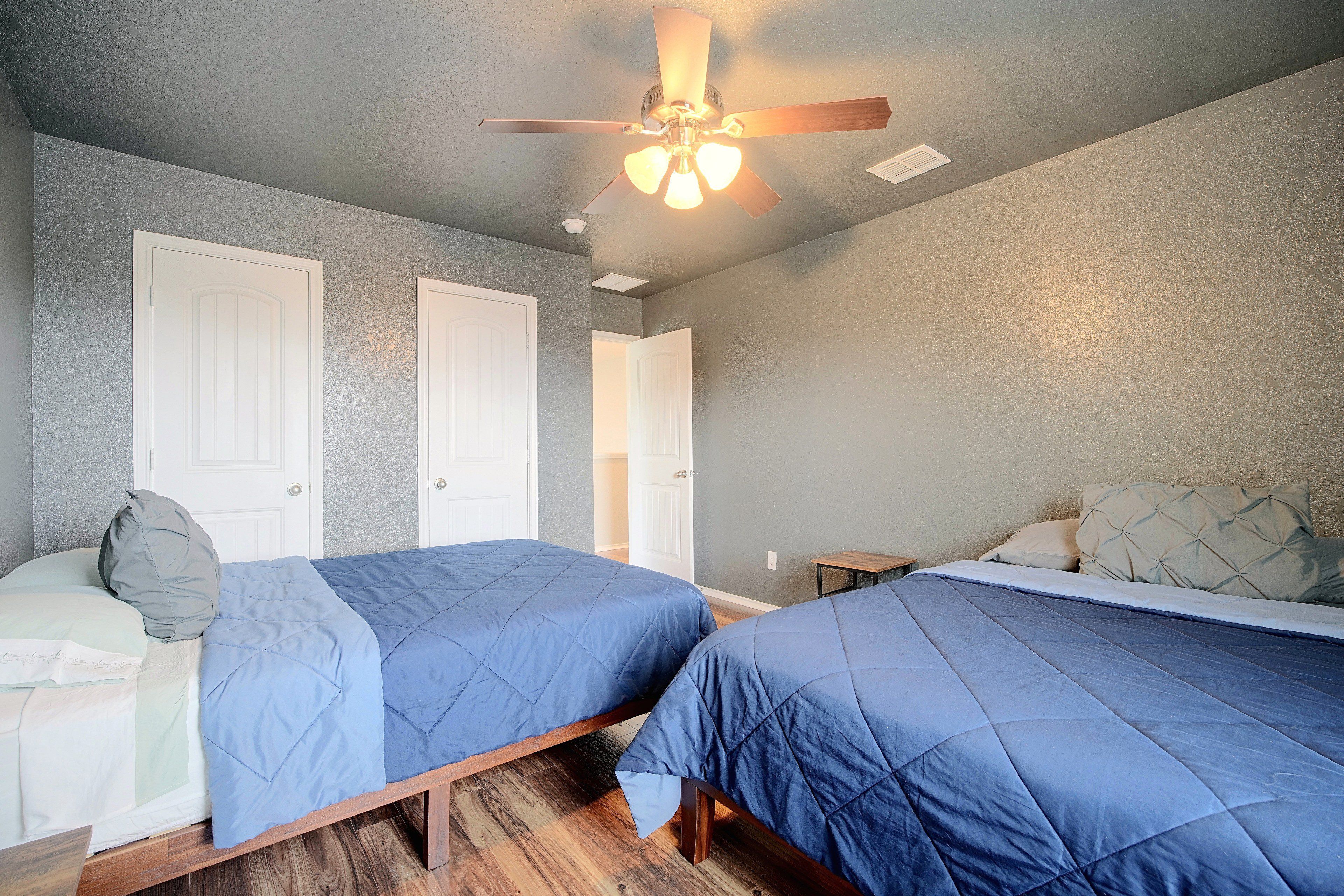 A bedroom with two beds, a ceiling fan, and a door.
