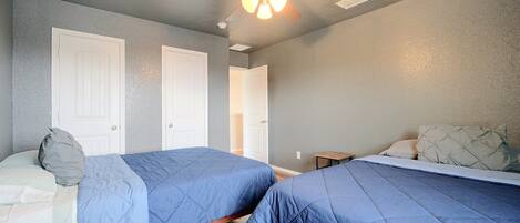 A bedroom with two beds, a ceiling fan, and a door.