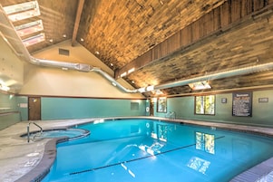 Ein Hallenbad mit Holzboden und -wänden, deutlich markierten Bahnen und einem Schild mit den Schwimmbadregeln.
