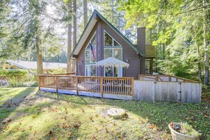 A cabin with a deck, surrounded by trees.