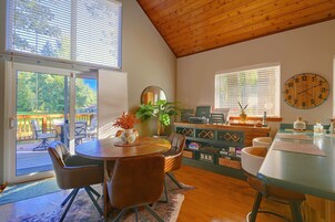A dining area with a round table, chairs, a plant, and a clock on the wall.