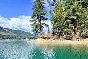 Un lago con aguas cristalinas, rodeado de un bosque denso y montañas al fondo.