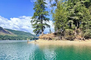 Un lago con aguas cristalinas, rodeado de un bosque denso y montañas al fondo.