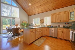 A kitchen with wooden cabinets, a dining area with a table and chairs, and large windows.