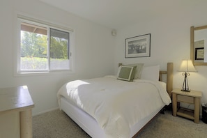 A bedroom with a bed, a bedside table with a lamp, a window, and a framed picture on the wall. - Walk to Snow King & Jackson Town Square! Cozy Unit (Jackson)