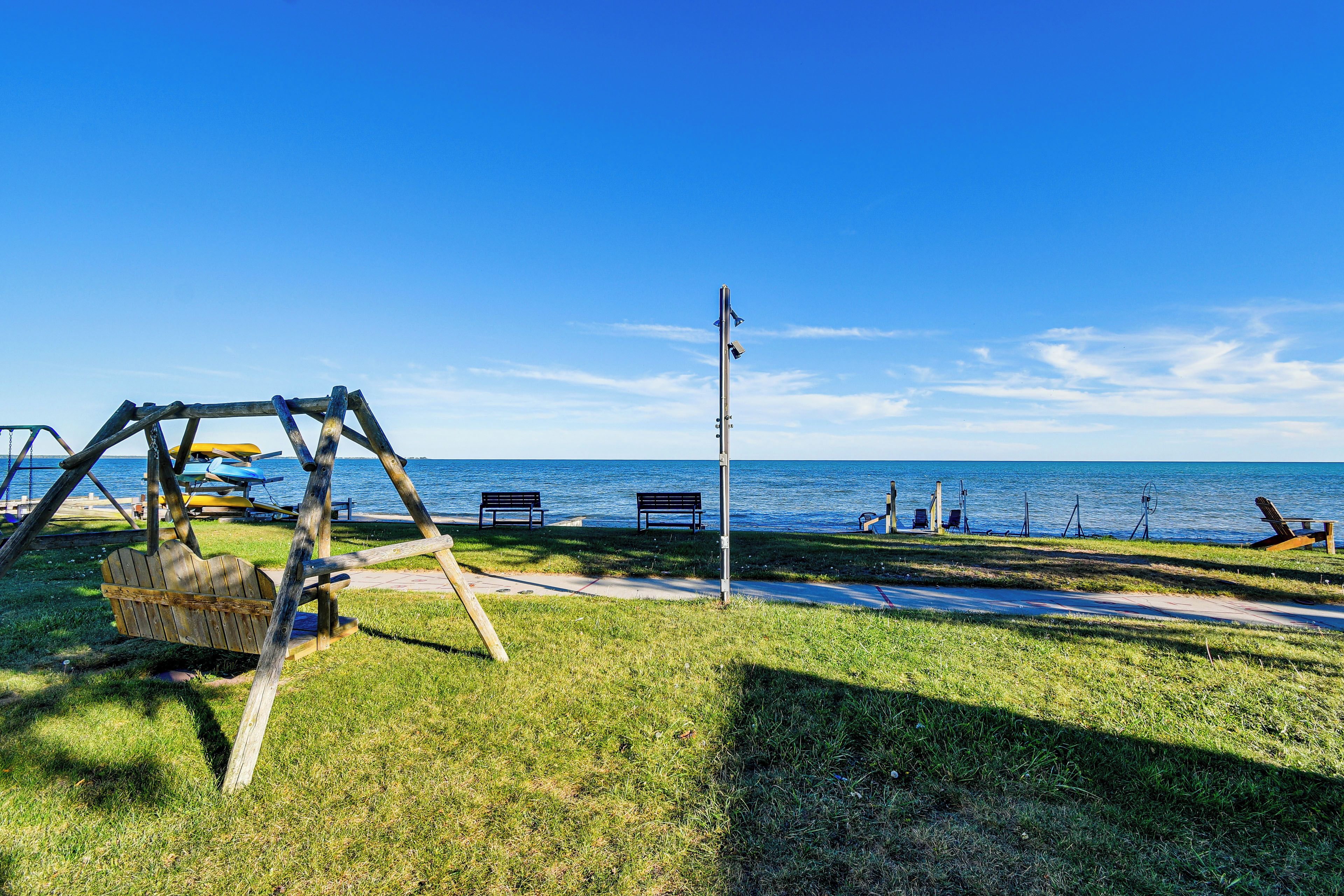 A park with a swing set, benches, and a view of the sea.