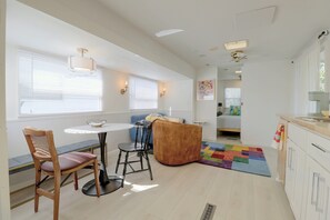 Cozinha moderna com área de refeições, sofá e tapete colorido.