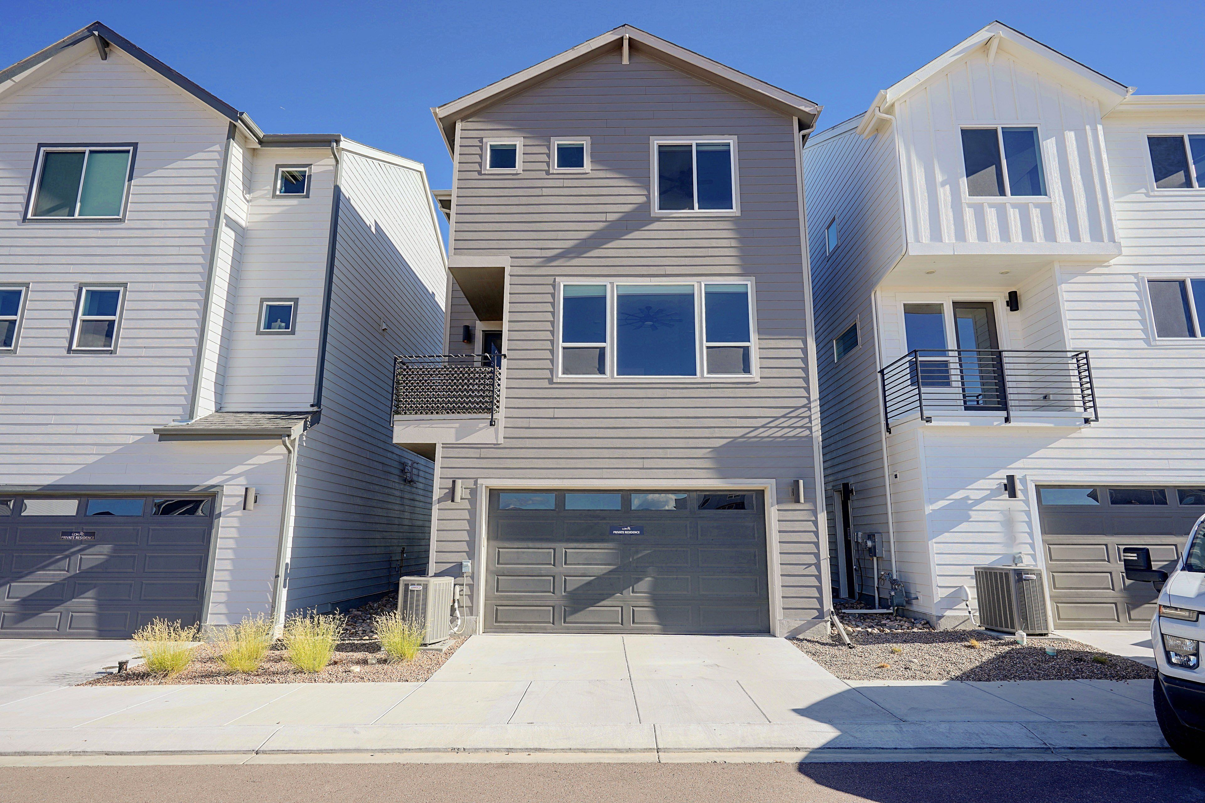 A row of townhouses with attached garages, a central entrance, and a small balcony on the second floor.