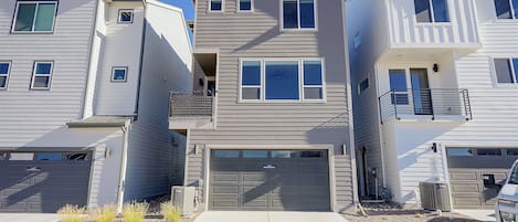 A row of townhouses with attached garages, a central entrance, and a small balcony on the second floor.
