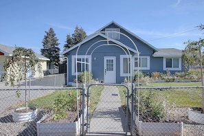 A residential house with a front yard, a gated entrance, and a clear sky.
