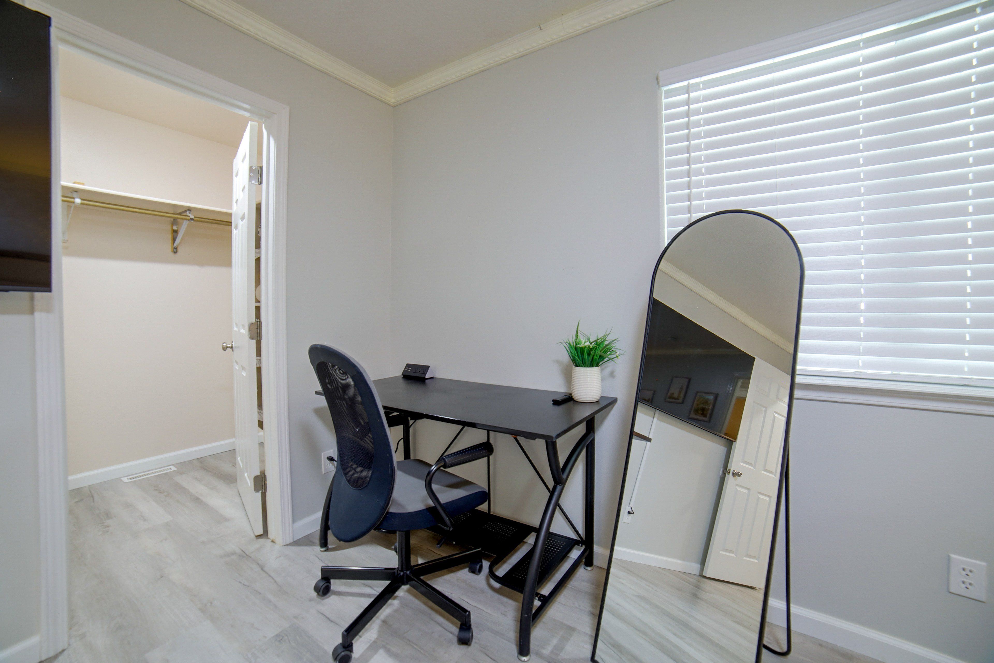 A small office space with a desk, chair, and a mirror.