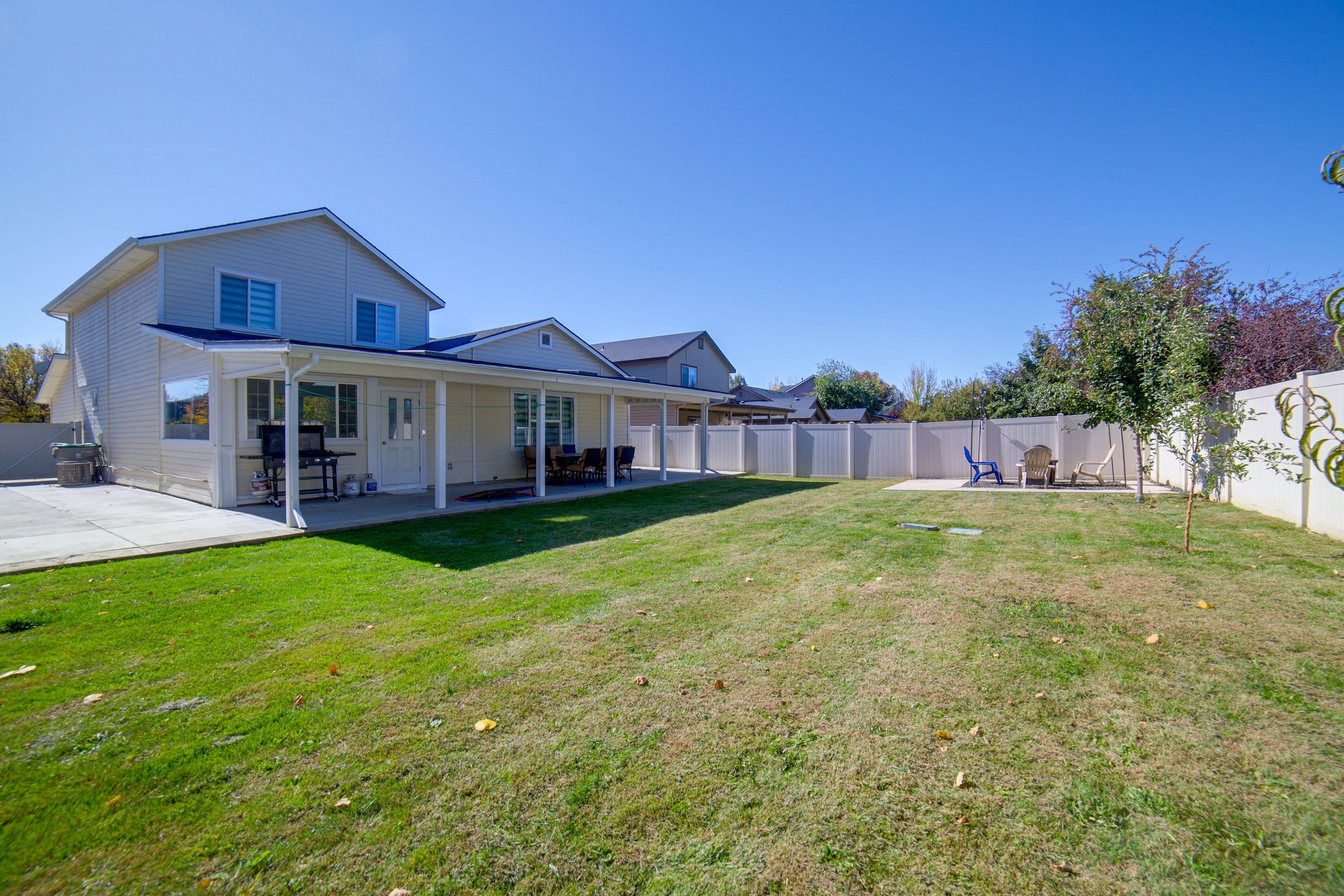 A residential property with a covered patio, a lawn, and a fenced backyard.