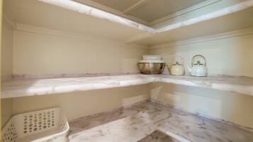 A kitchen with marble countertops and shelves, a basket, and a kettle.