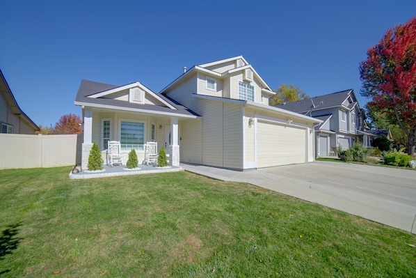 A two-story residential house with a garage, a front porch with a bench, and a well-maintained lawn. - The Boise Retreat Spacious Home, Game Room! (Boise)