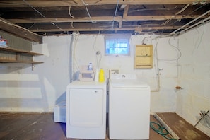 A laundry room with two washing machines, a window, and various electrical outlets and wiring.