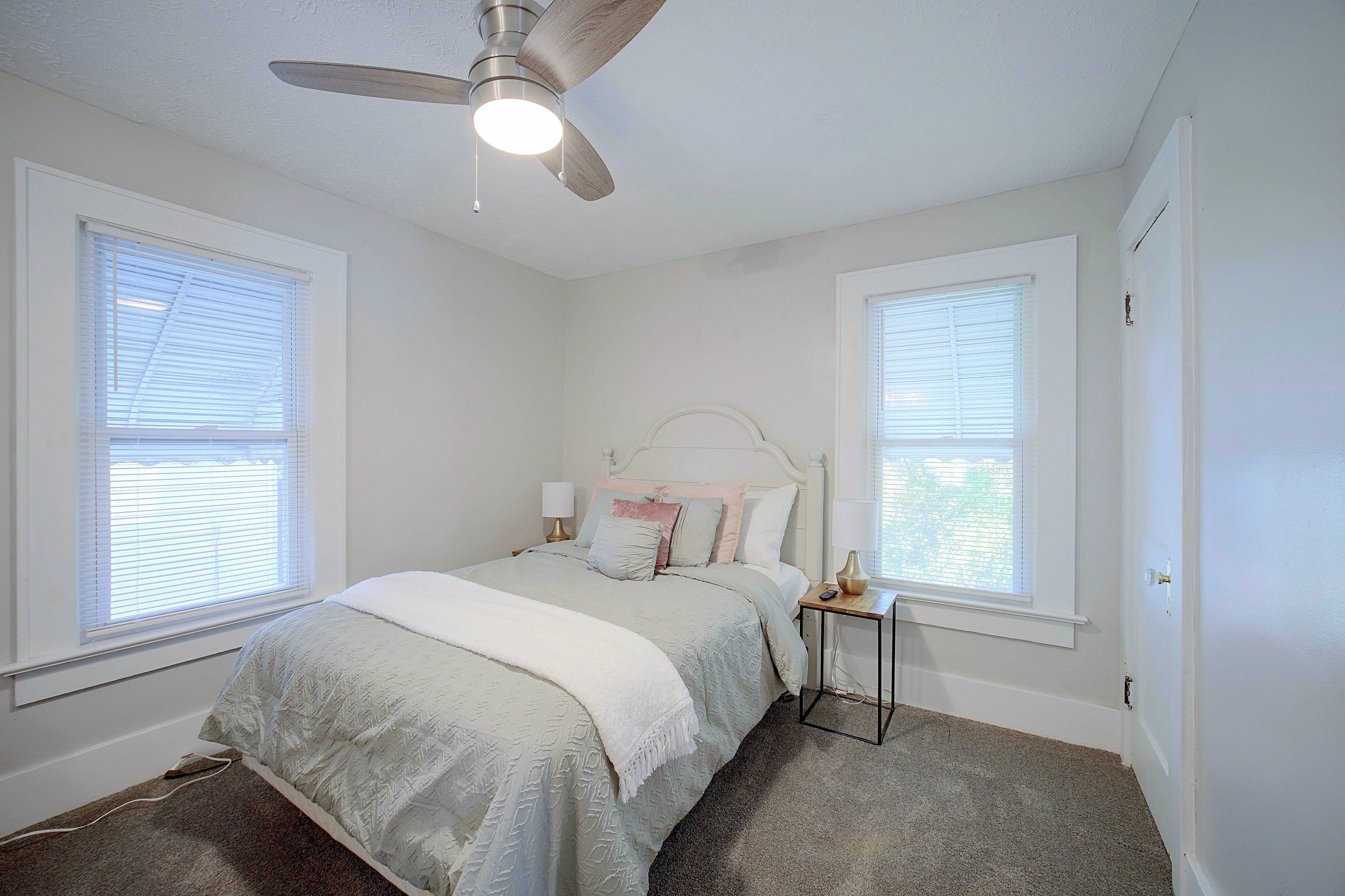 A bedroom with a bed, a nightstand, a lamp, and a ceiling fan.