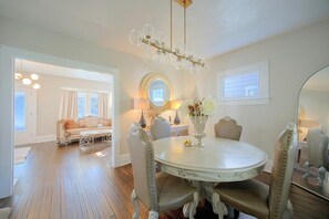 A dining area with a round table, chairs, and a chandelier.