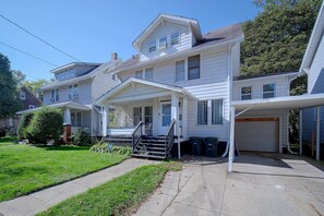 A two-story residential house with a front porch, a garage, and a well-maintained lawn. - 1 Mi to Akron Zoo! Charming Home w/ Yard (Akron)