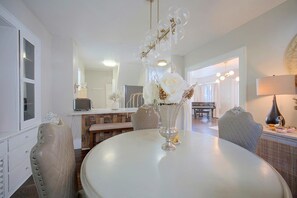 A dining area with a round table, chairs, a vase with flowers, a piano, and a lamp. - 1 Mi to Akron Zoo! Charming Home w/ Yard (Akron)