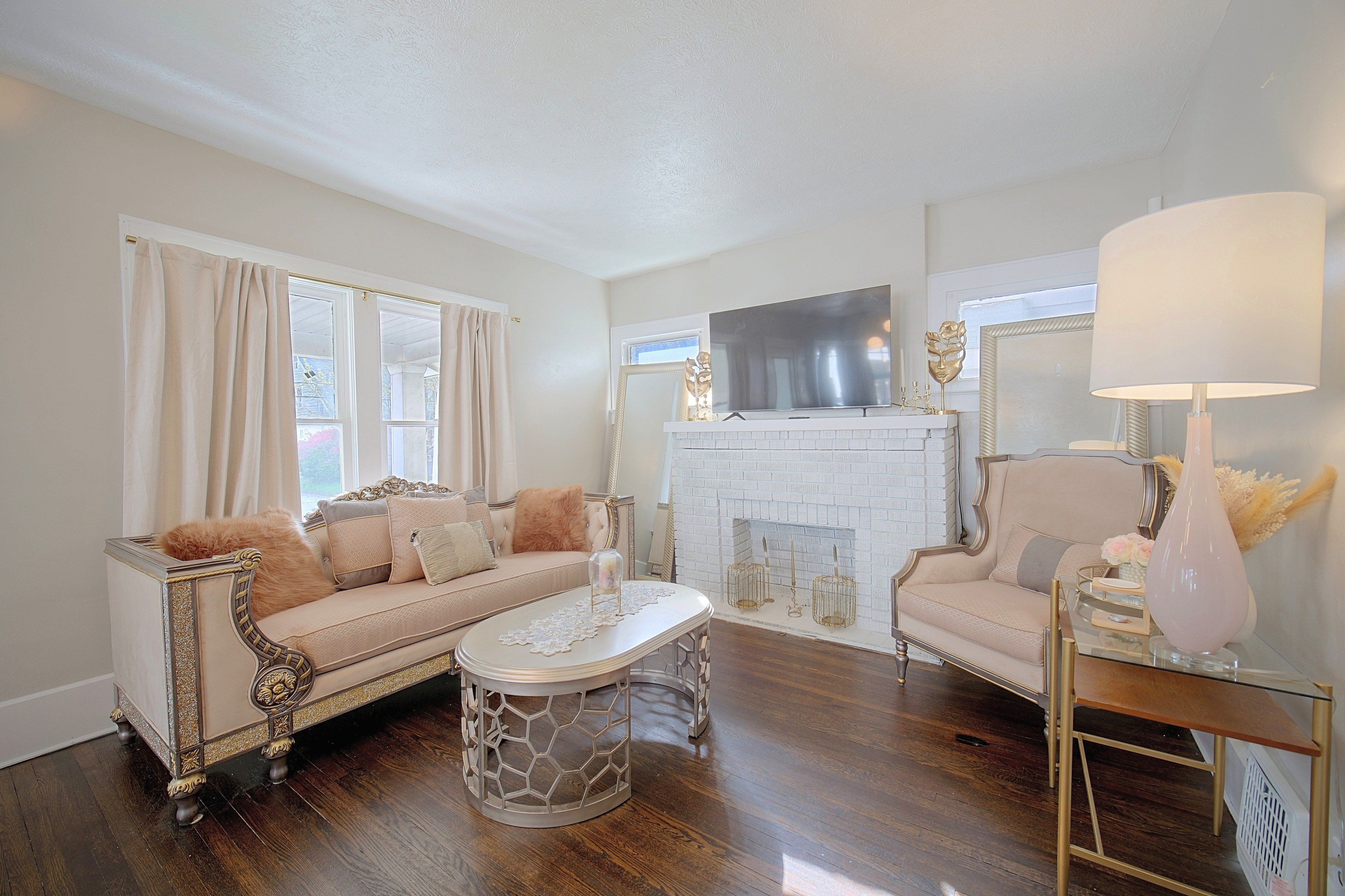Una sala de estar con sofá, sillón, mesa de centro, chimenea y televisor.