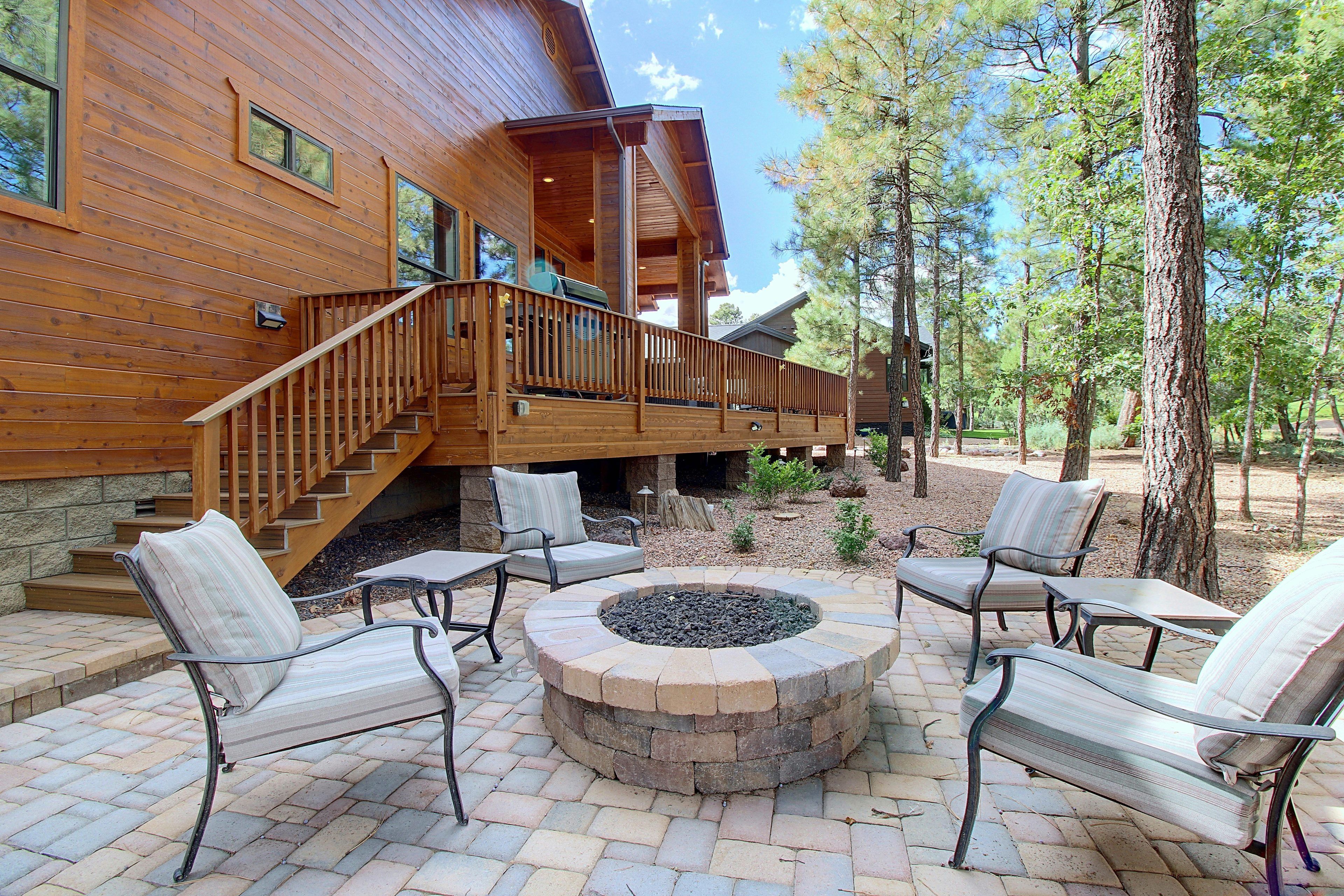 A wooden cabin with a deck, outdoor seating, and a fire pit.