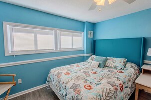 Un dormitorio con una cama, una ventana, una obra de arte en la pared y una mesita de noche.
