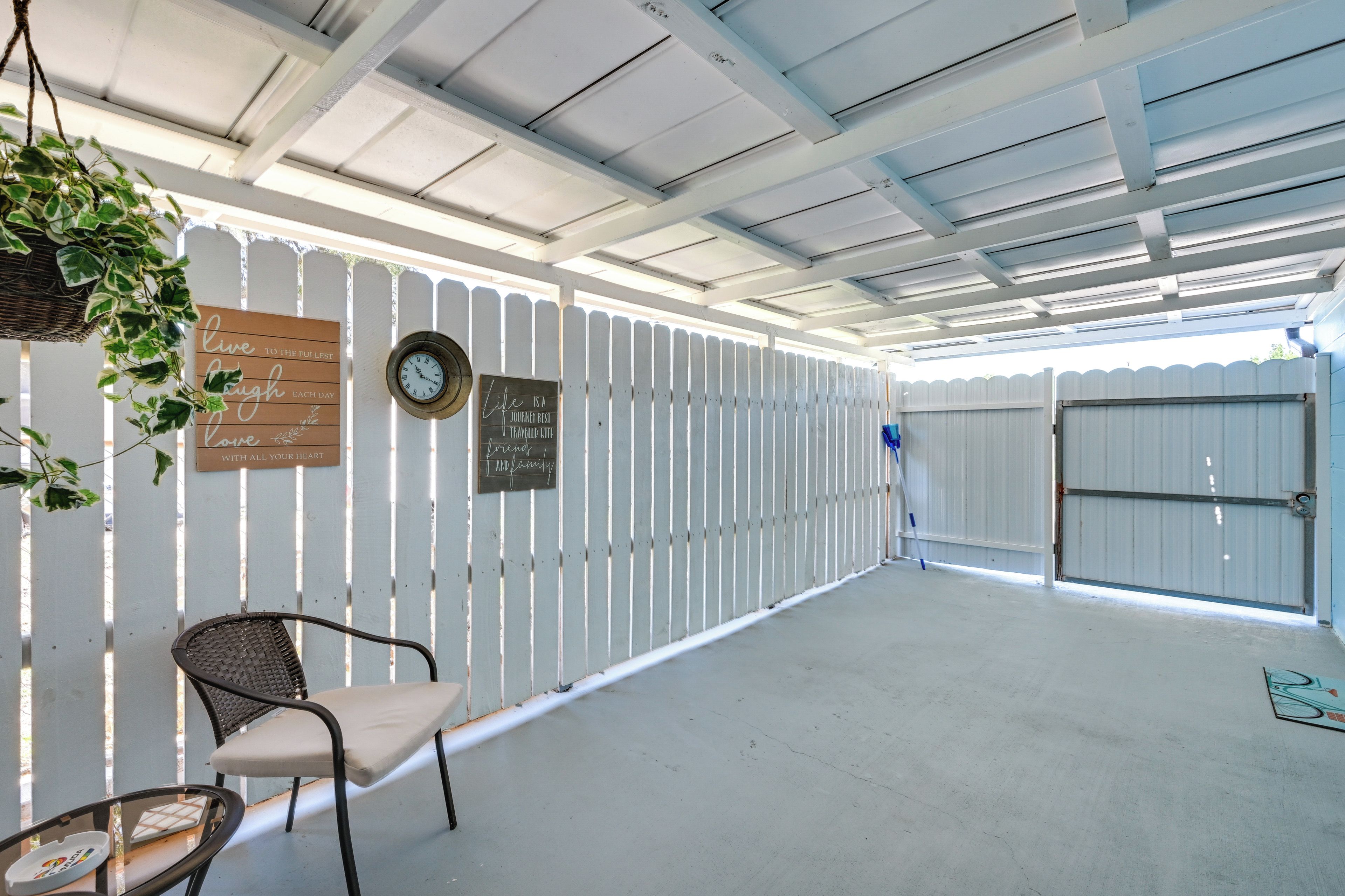 A covered outdoor area with a white fence, a clock, and motivational signs.
