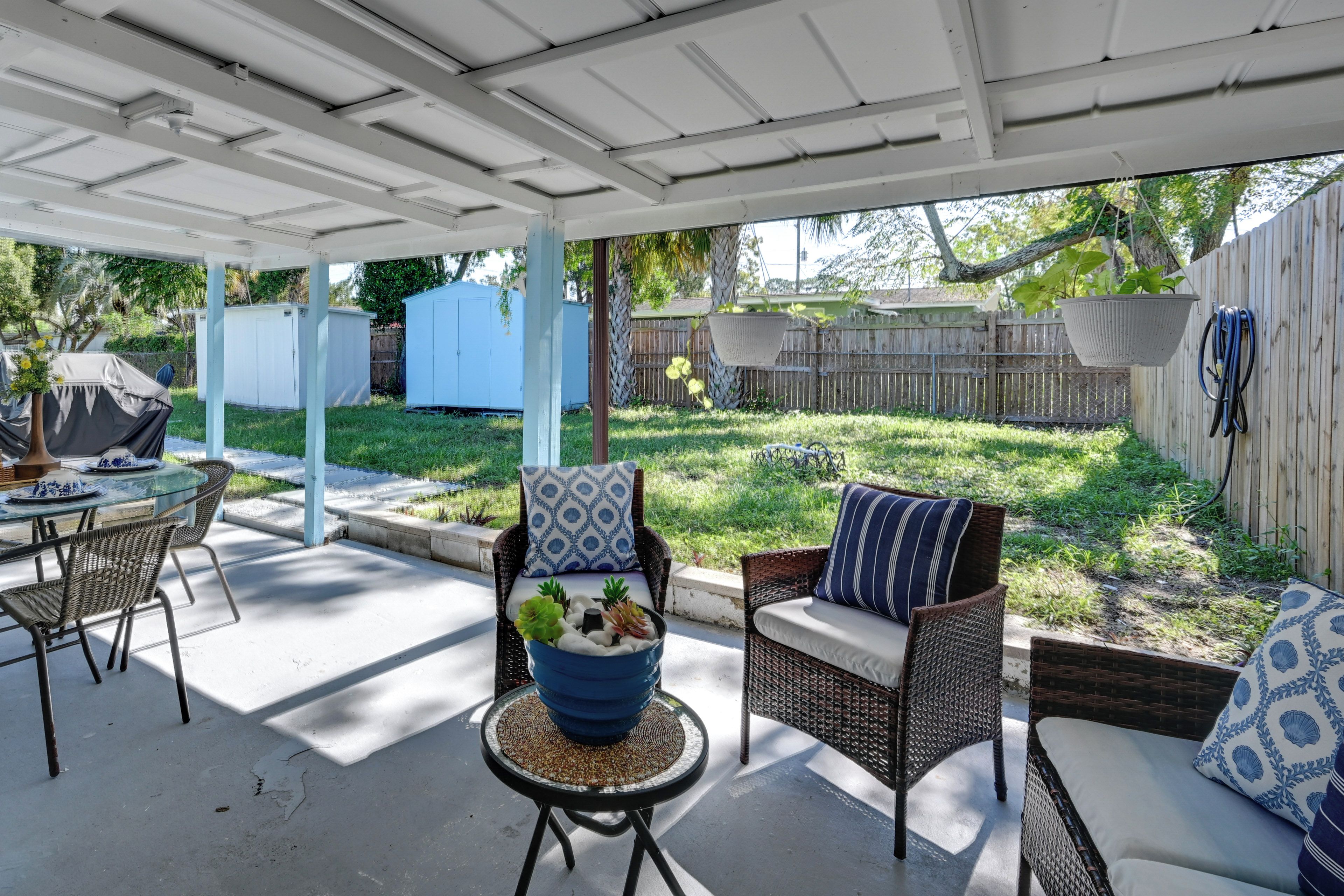 A covered patio area with outdoor furniture, including a table and two chairs, and a hanging plant basket.
