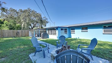 Une maison bleue dotée d’un patio aménagé avec des fauteuils Adirondack et un foyer extérieur.