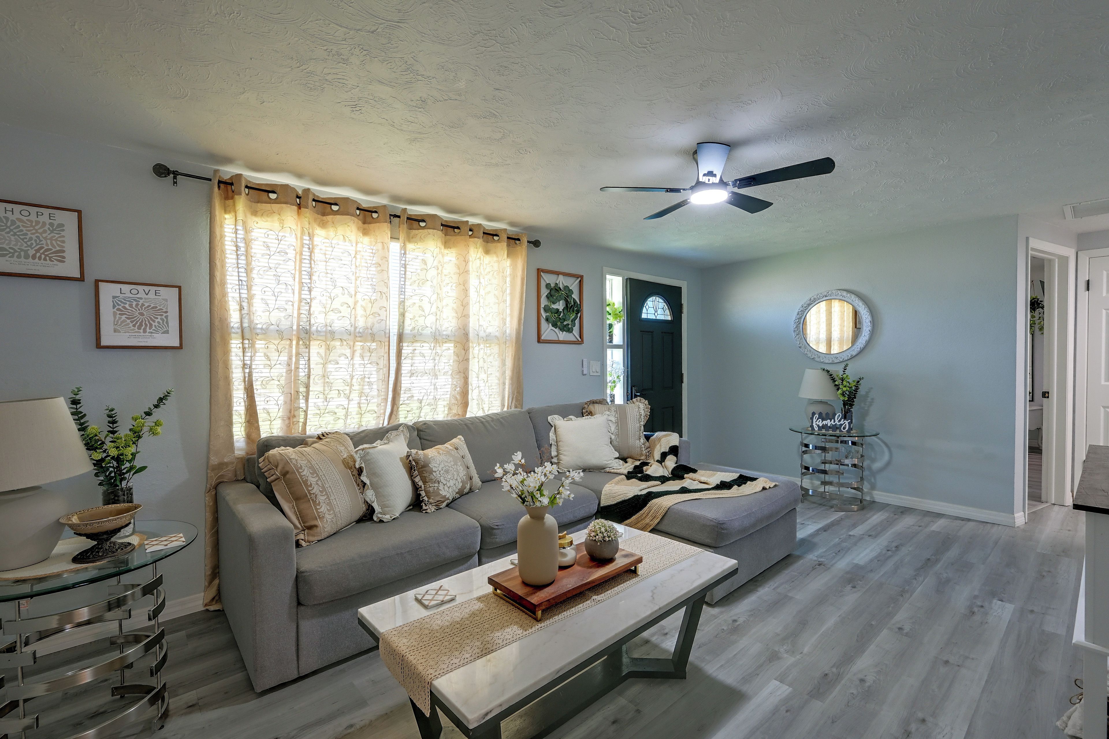 A living room with a grey sofa, a coffee table, and a ceiling fan.