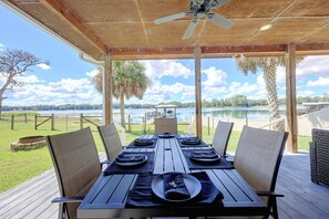An outdoor dining area with a table set for four, overlooking a lake.