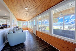 A spacious room with a wooden ceiling, large windows, and a seating area with a sofa and chairs.