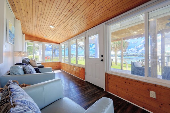A room with a wooden ceiling, large windows, and a view of the outdoors.