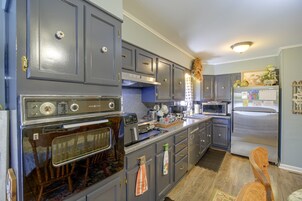 A kitchen with grey cabinets, a stainless steel refrigerator, a microwave, and a stove.