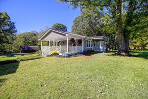 A single-story house with a porch, surrounded by a well-maintained lawn and trees.