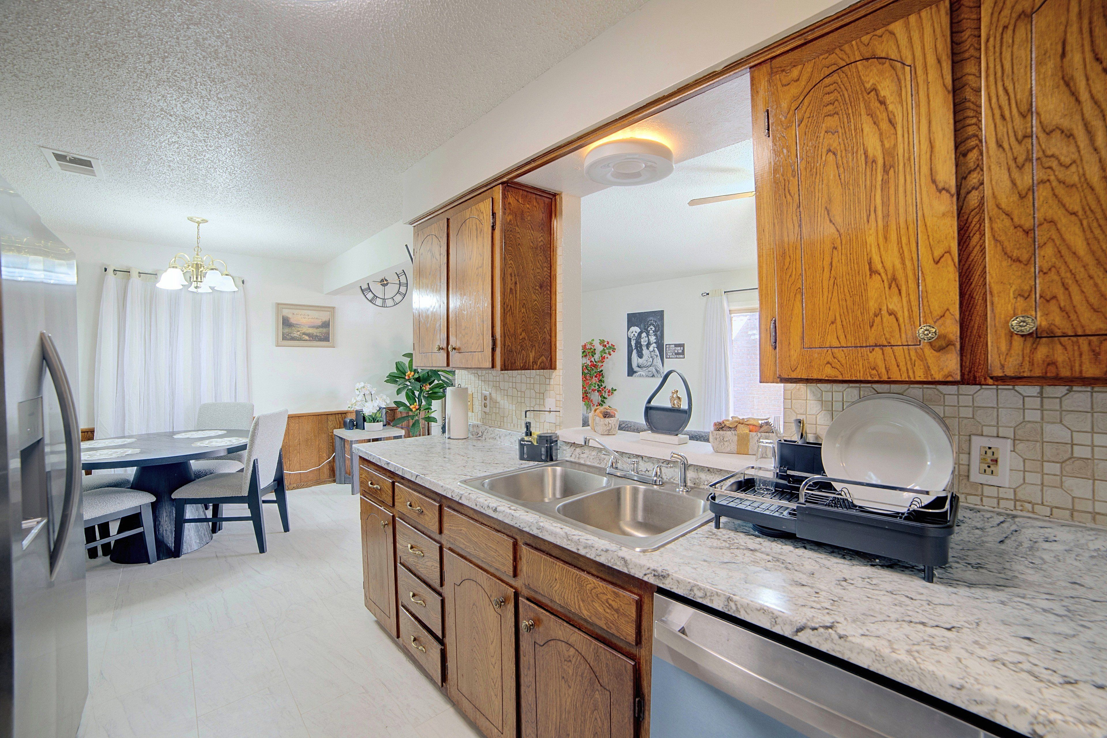 A kitchen with wooden cabinets, a marble countertop, a sink, and a dishwasher.