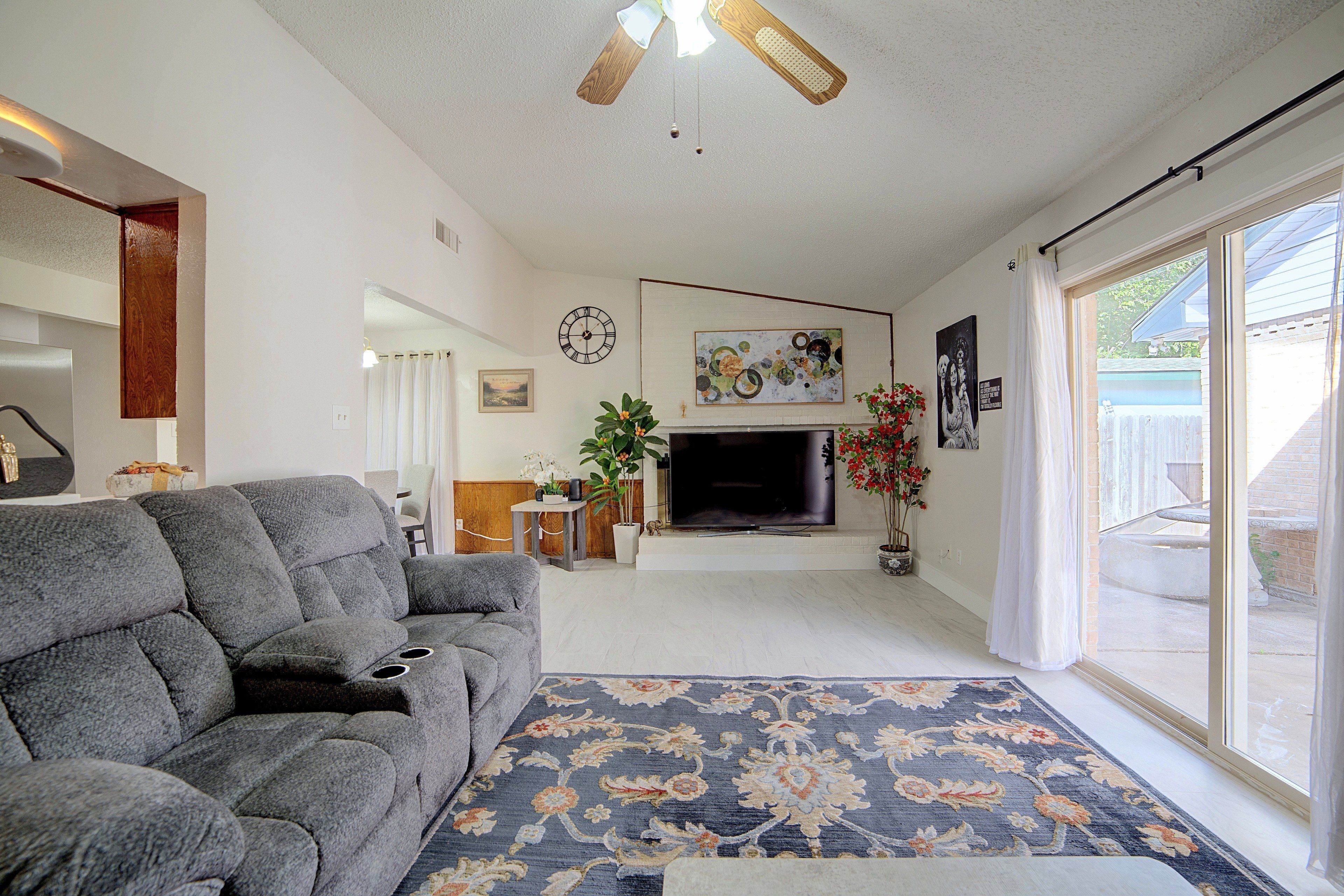 A living room with a gray sofa, a fireplace, a television, and a large window.