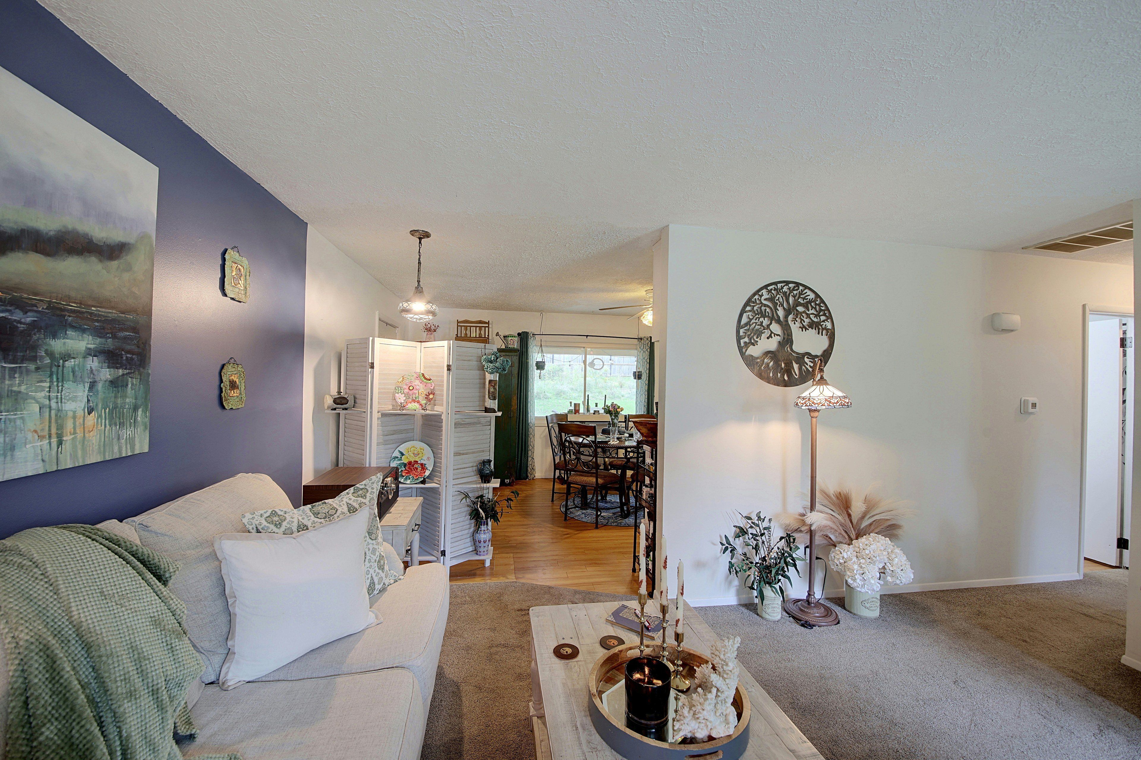 A living room with a sofa, a coffee table, and a dining area with chairs and a table.