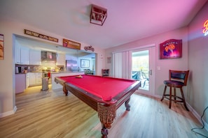 A pool table in a room with a kitchen and a billiard table.