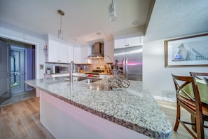 A modern kitchen with granite countertops, stainless steel appliances, and white cabinetry.