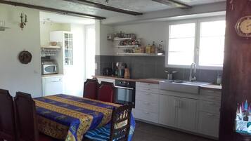 Een keuken met een eettafel, stoelen en een raam.