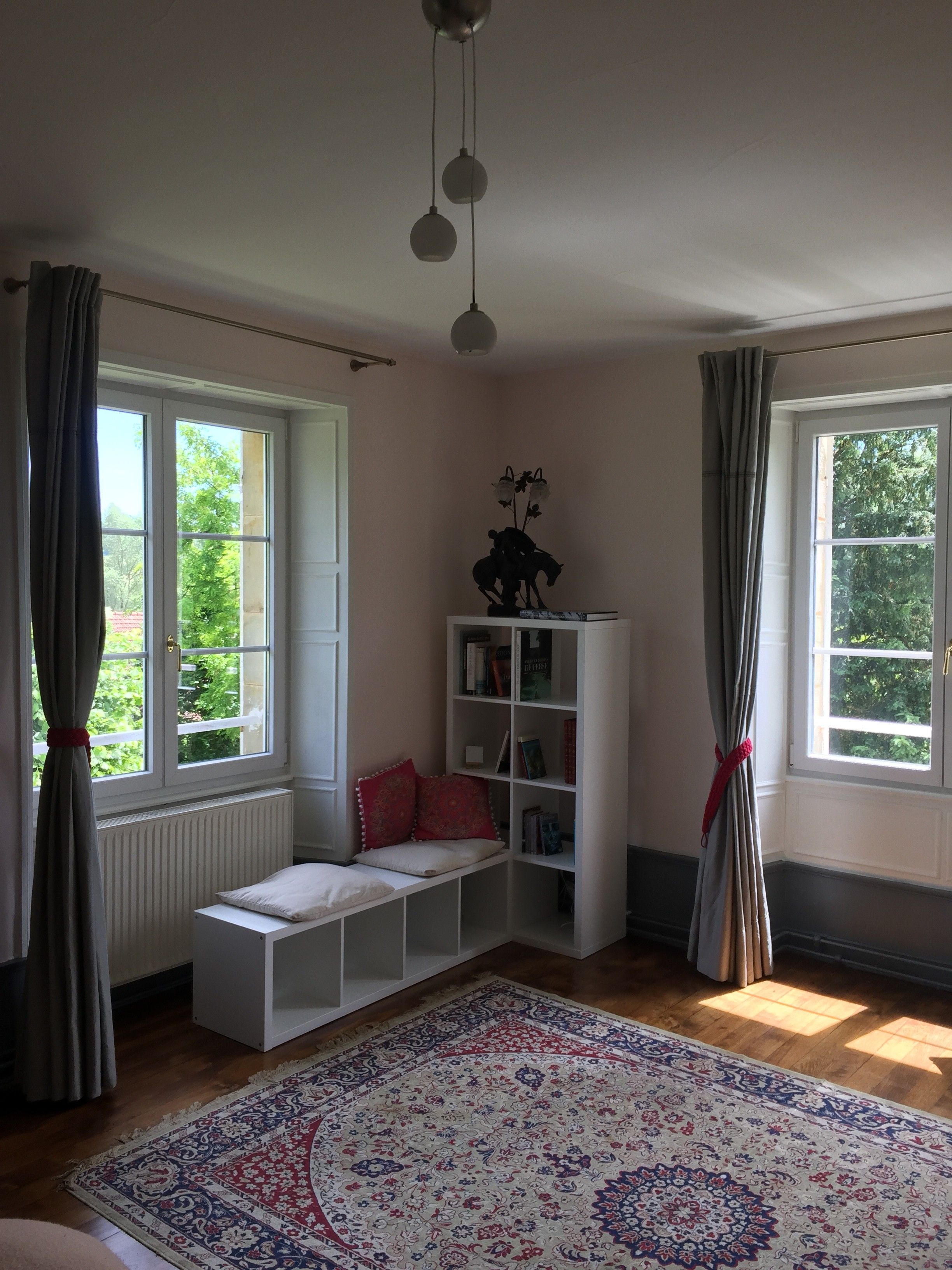 Una habitación con un banco blanco, una estantería y una alfombra estampada.
