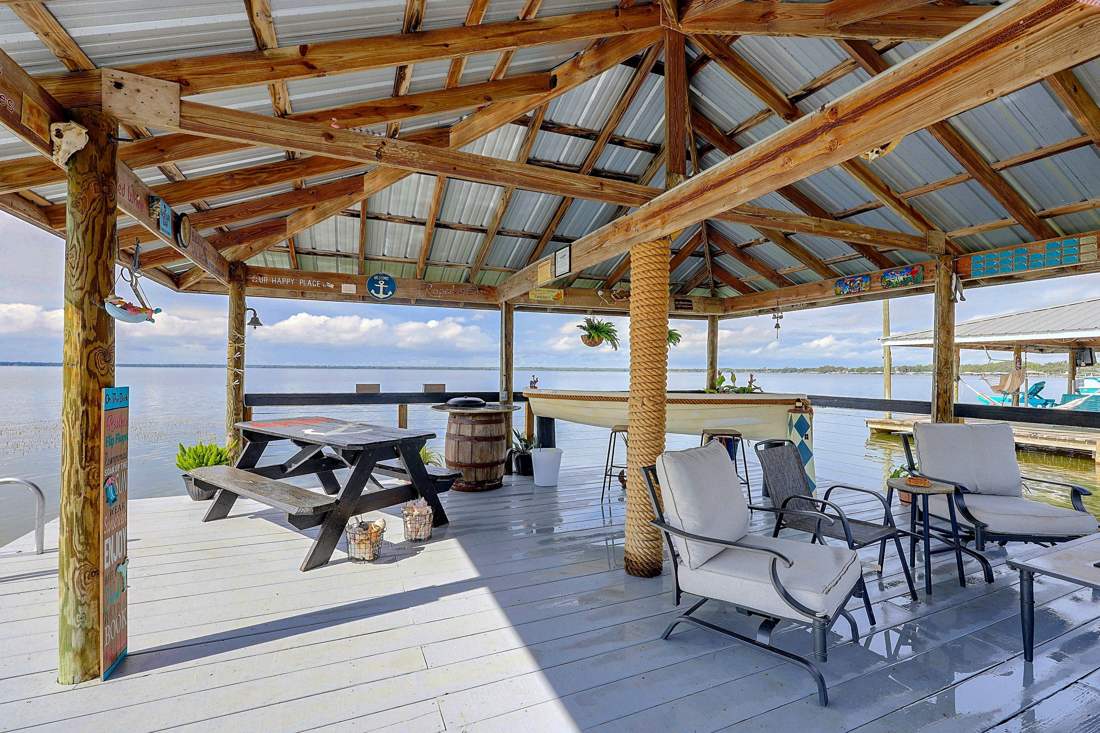 A wooden deck with a covered seating area overlooking a body of water.
