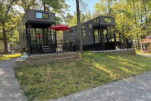 Two timber-style cabins with external staircases, a red umbrella, and a bear statue.