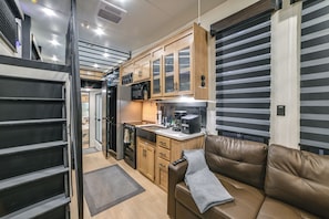 A compact kitchen with a refrigerator, microwave, and stove, a brown leather couch, and a sliding door closet. - 1 Mi to Kentucky Lake! 'special Place' Tiny Home (Springville)