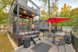 A compact, modern structure with a flat roof, a covered outdoor seating area, and a small pool.
