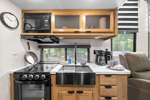 A compact kitchenette with a stove, oven, microwave, and a coffee maker.
