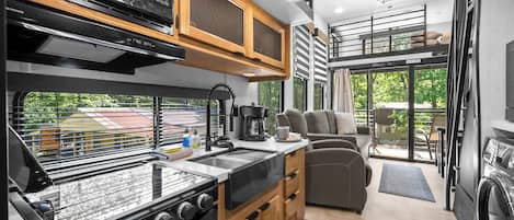 A compact kitchen with a stove, microwave, and wooden cabinets.